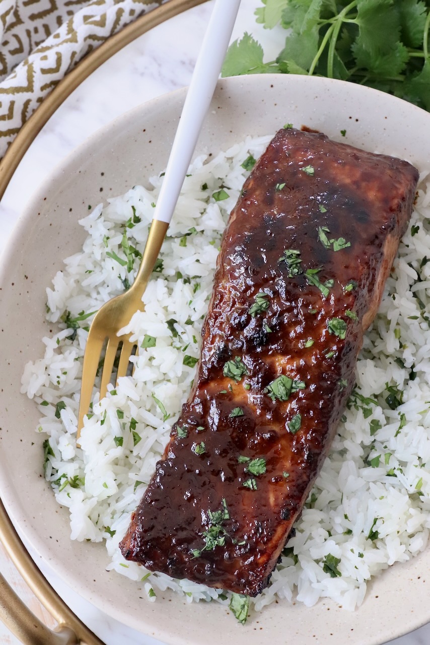 glazed salmon on top of rice in bowl with fork