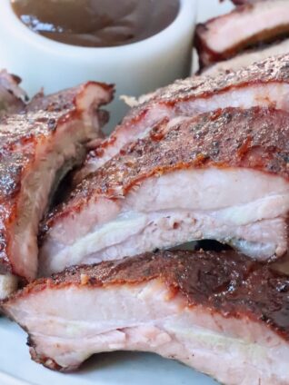 smoked pork ribs sliced on plate with bbq sauce