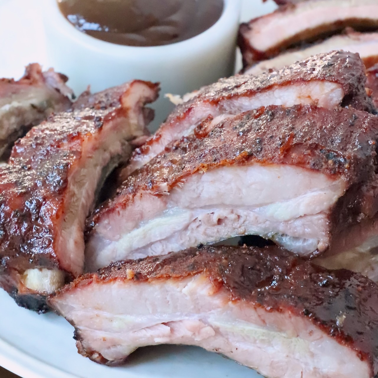 smoked pork ribs sliced on plate with bbq sauce