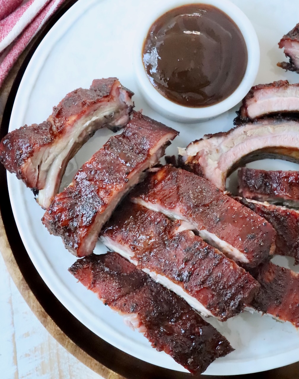 sliced, smoked baby back ribs with bbq sauce on plate