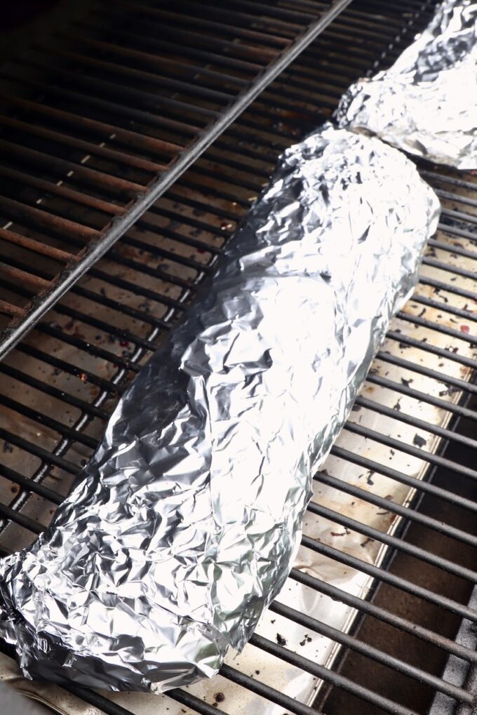 rack of ribs wrapped in foil on a smoker