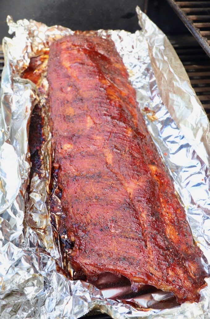smoked baby back ribs on a piece of foil in a smoker