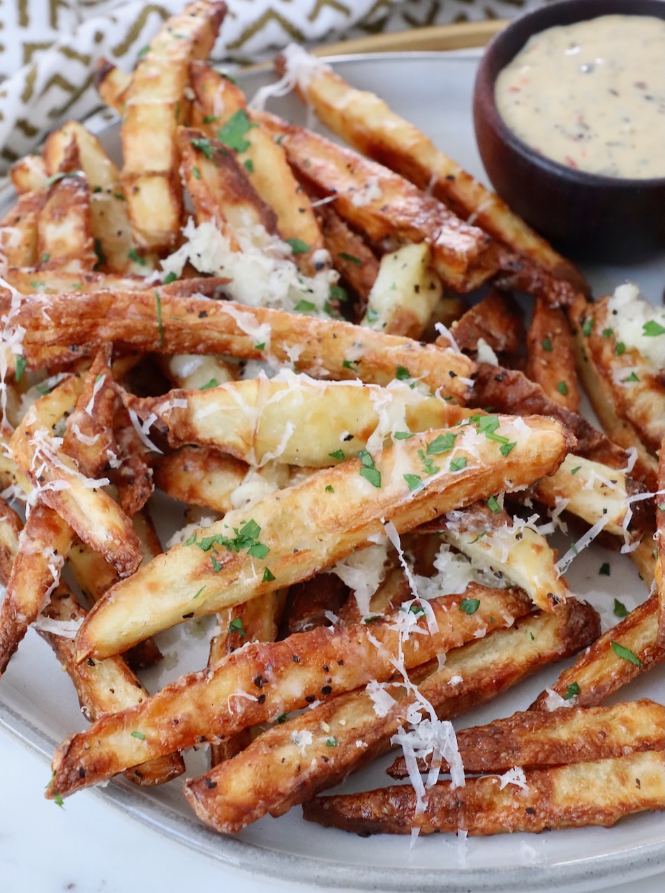 parmesan truffle fries on plate with a small bowl of dipping sauce on the side