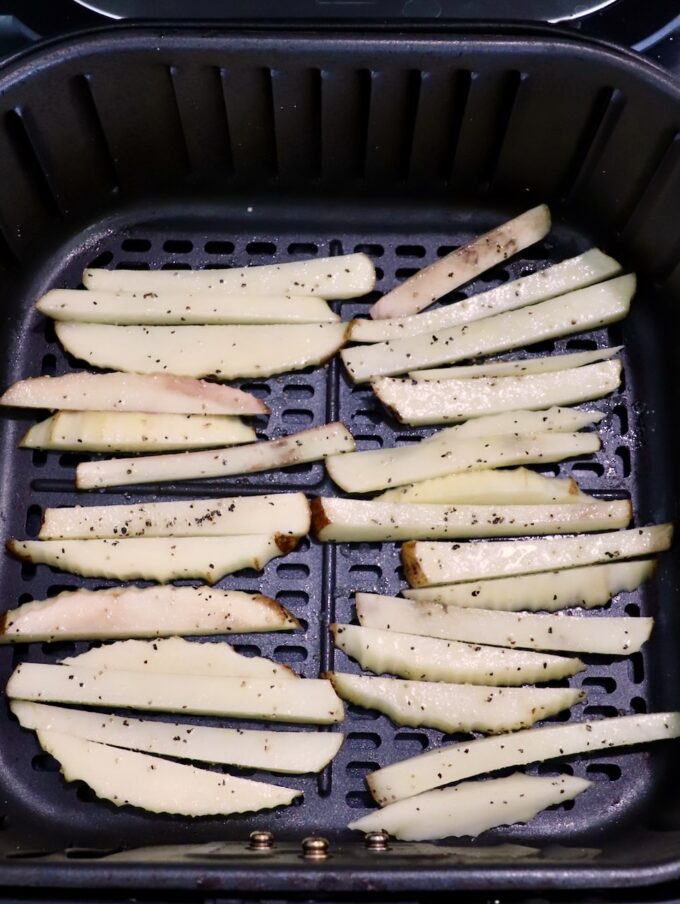 seasoned sliced potatoes in air fryer basket