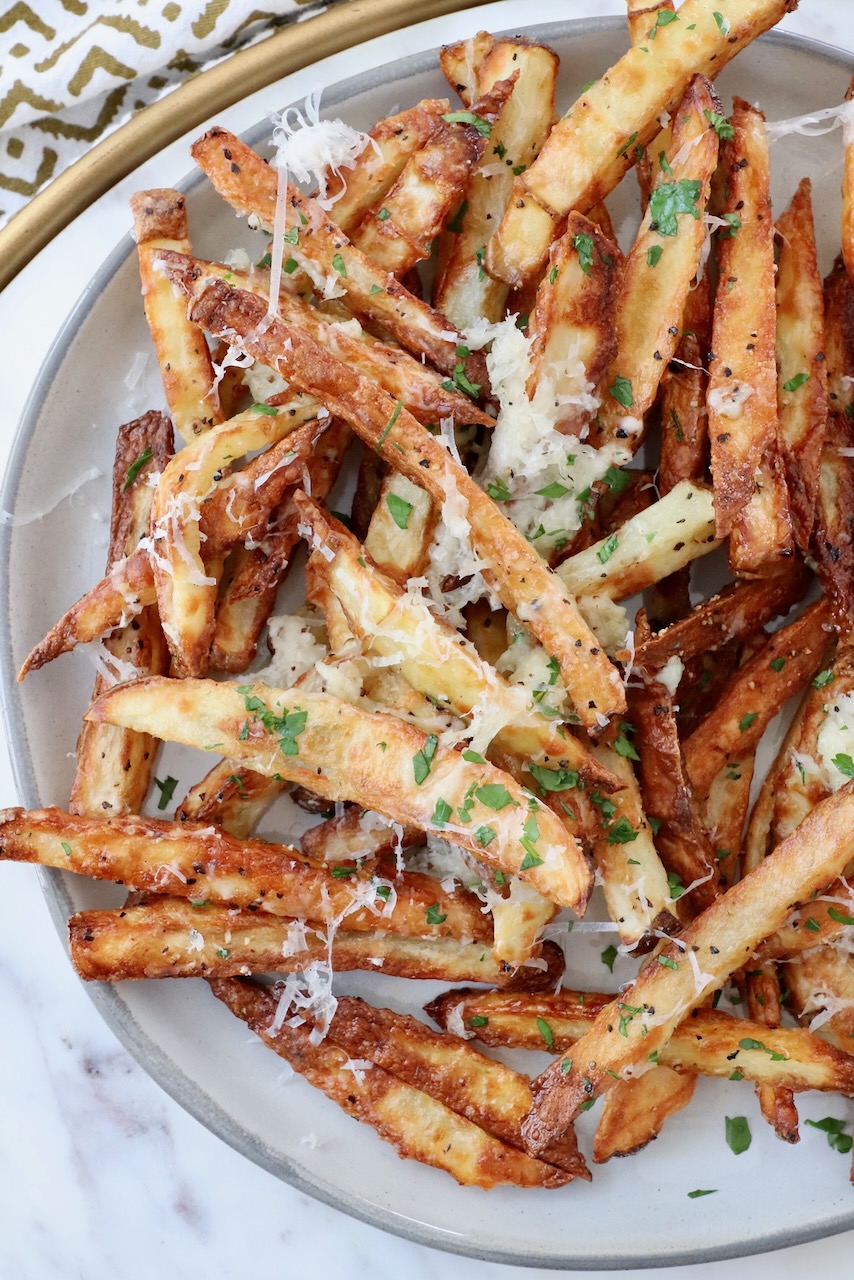 cooked french fries on plate topped with grated parmesan cheese