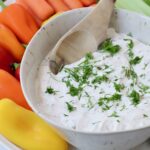 creamy vegetable dip in bowl topped with fresh chopped dill