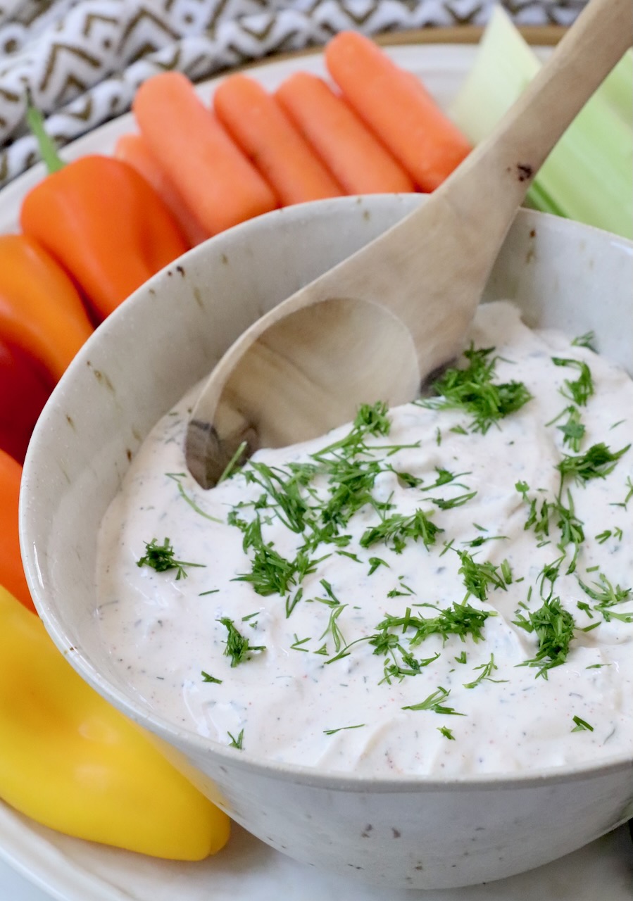 creamy dip topped with chopped dill in bowl with spoon