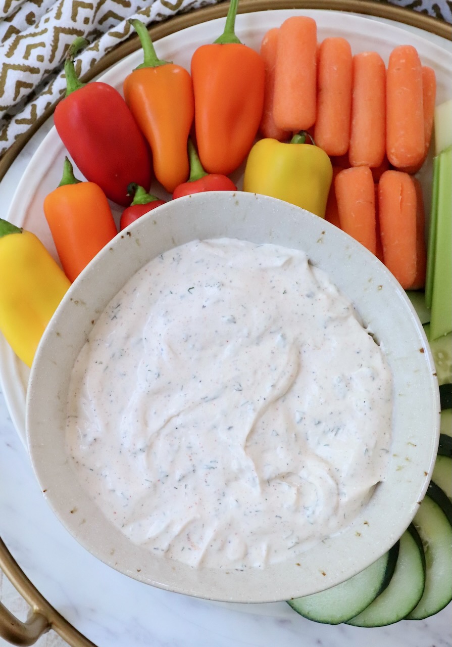 creamy vegetable dip in a bowl surrounded by fresh vegetables