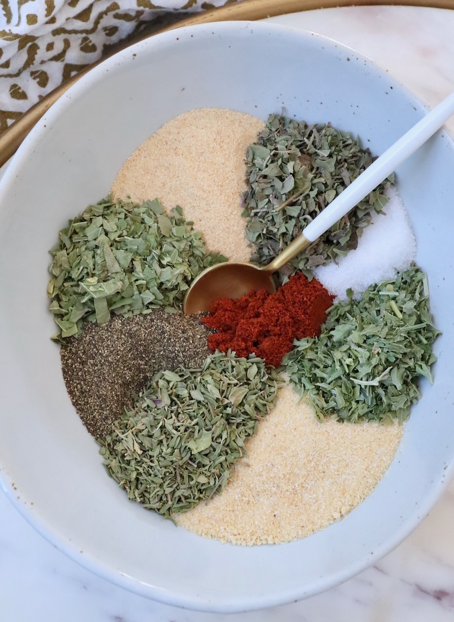 dried herbs and spices separated in a bowl with a spoon