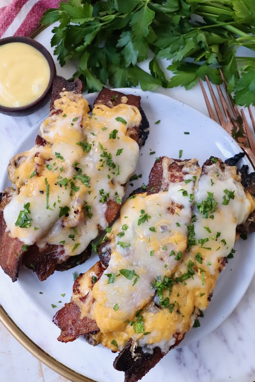 grilled chicken topped with slices of bacon and melted cheese on plate