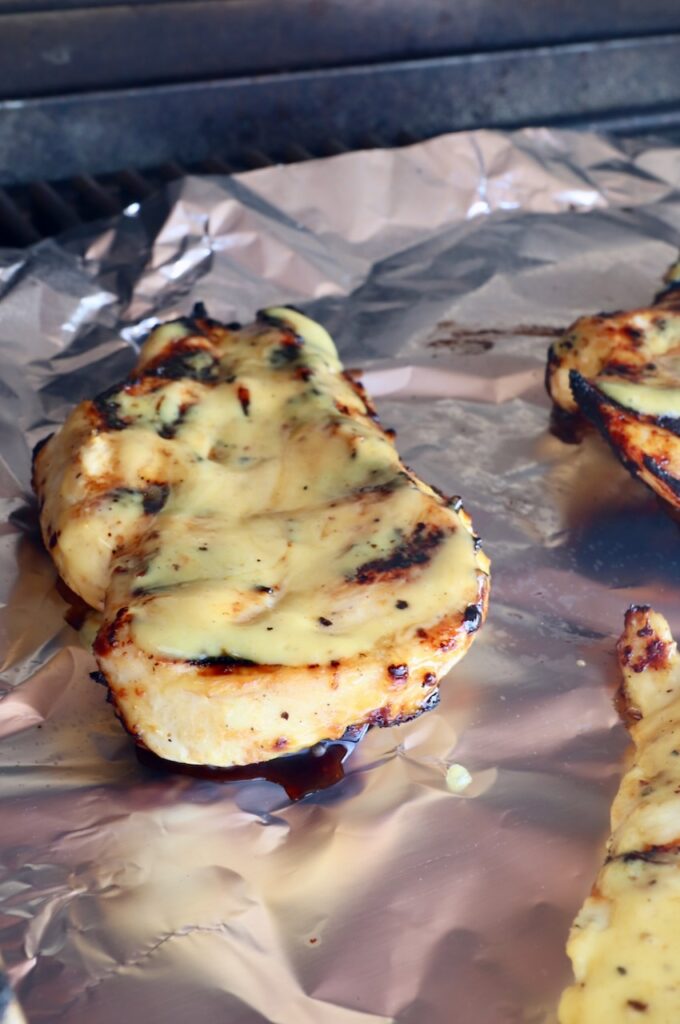 grilled chicken glazed with honey mustard on a piece of foil in a grill