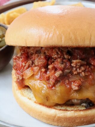cheeseburger topped with chili on plate