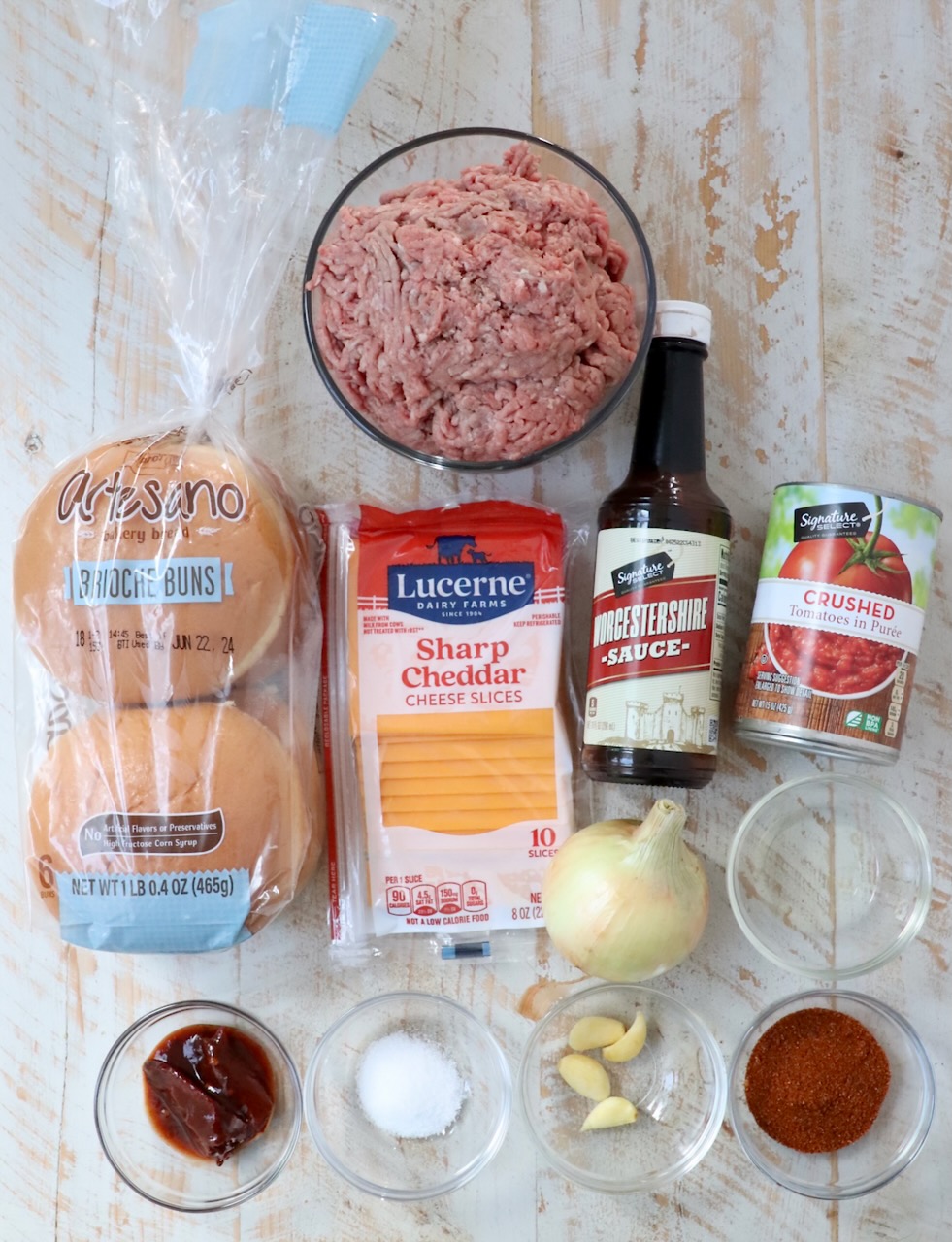 ingredients for chili cheeseburgers on white wood board