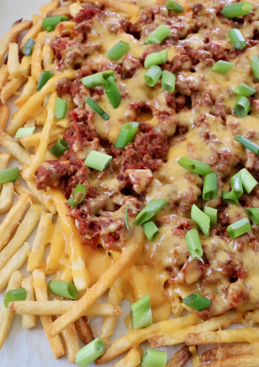 chili cheese fries on parchment lined baking sheet