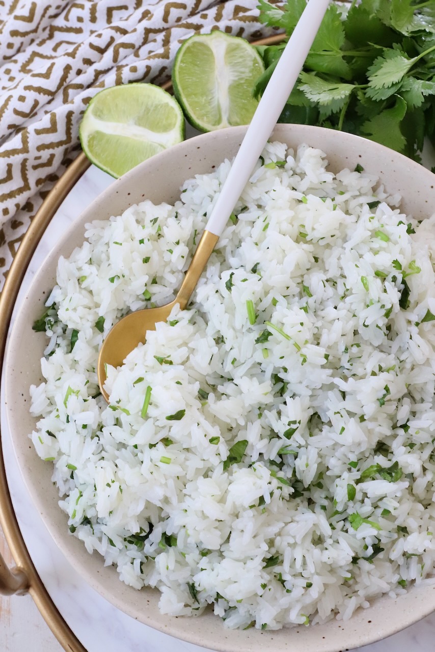 cooked white rice mixed with cilantro in bowl with spoon