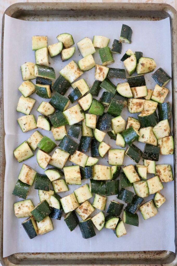 seasoned diced zucchini on parchment lined baking sheet