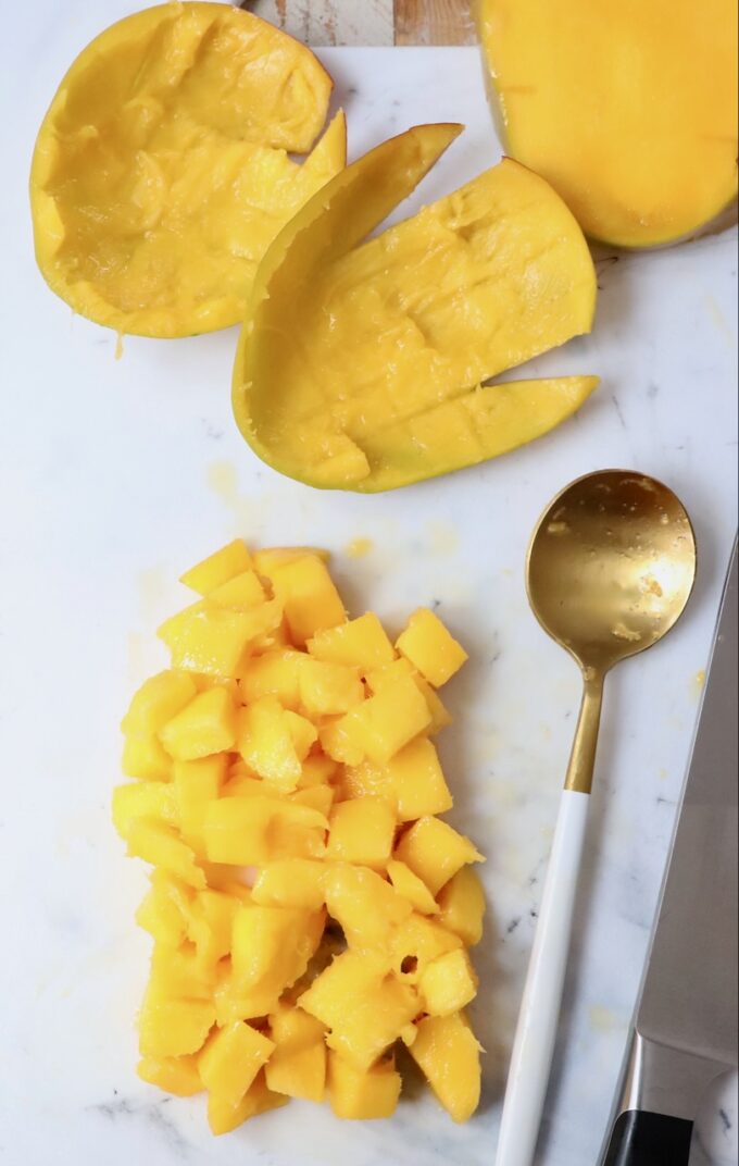 diced mango on cutting board with spoon