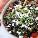 black beans in bowl, topped with crumbled cheese and fresh cilantro