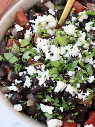 black beans in bowl, topped with crumbled cheese and fresh cilantro