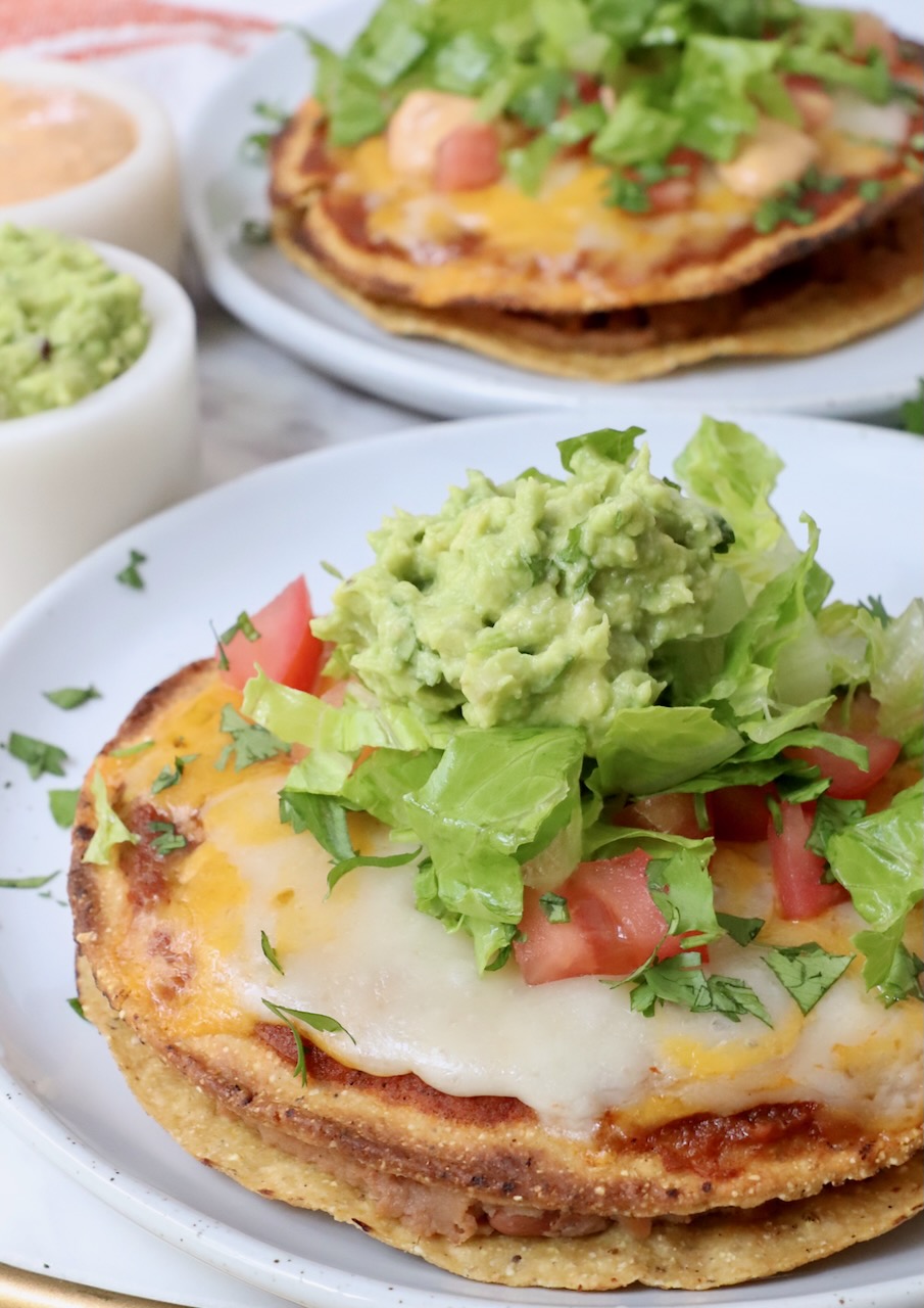 Mexican pizza on plate topped with shredded lettuce and guacamole