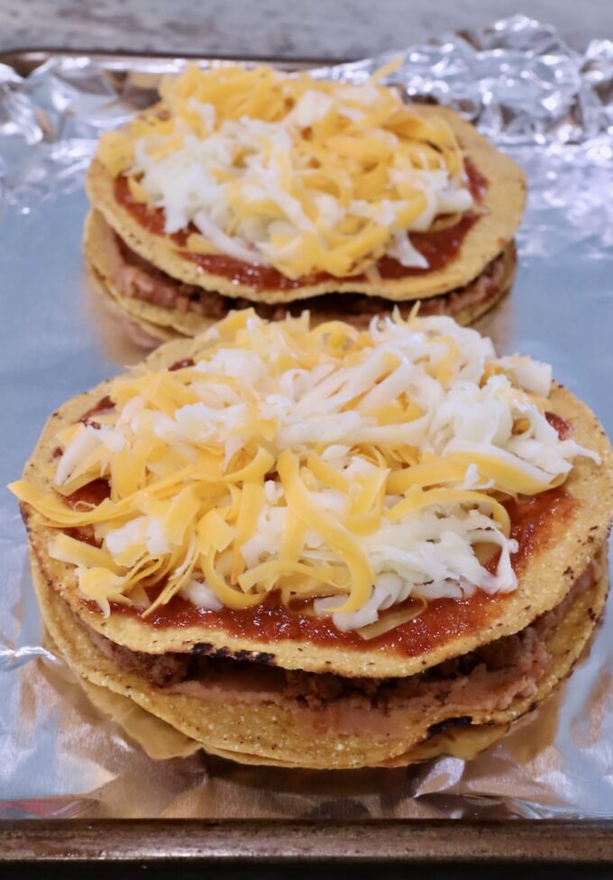 uncooked Mexican pizzas on a foil-lined baking sheet