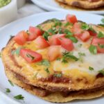 Mexican pizza on plate topped with diced tomatoes and fresh cilantro