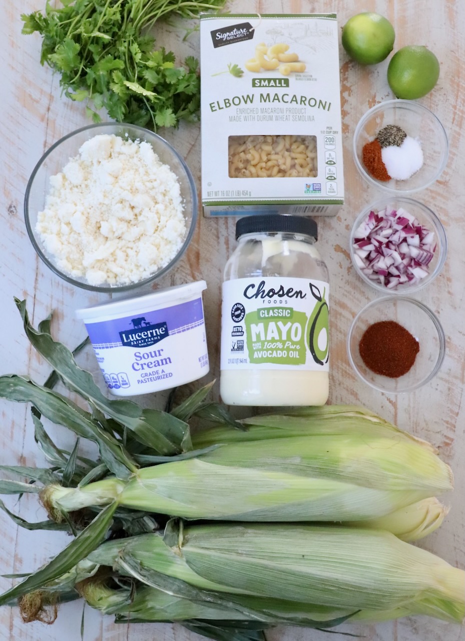 ingredients for Mexican street corn pasta salad on white wood board