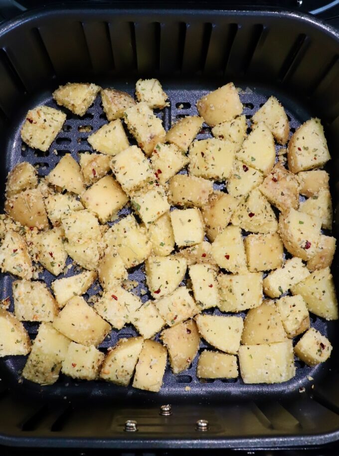 seasoned cubes of potatoes in an air fryer basket