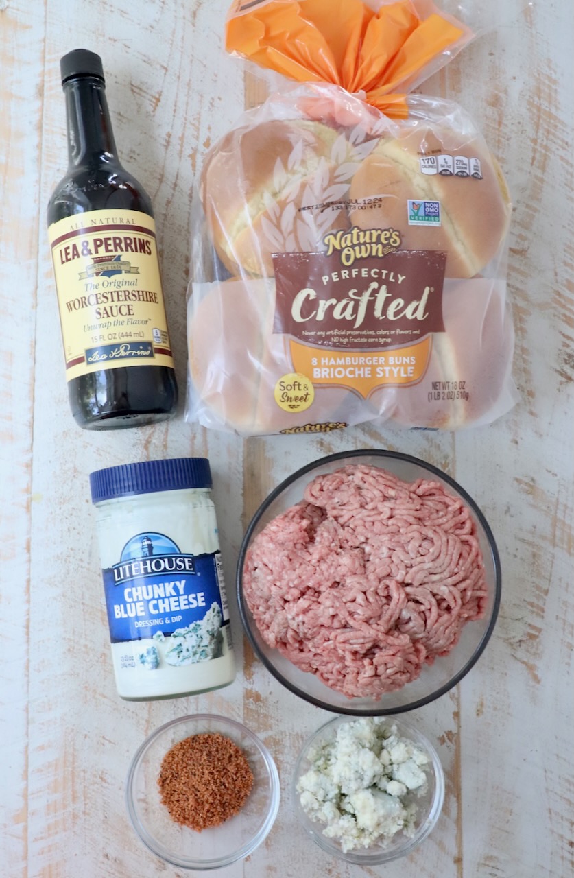 ingredients for blue cheese burgers on white wood board