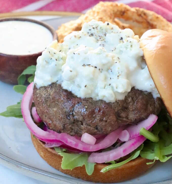 grilled burger patty topped with blue cheese sauce on plate