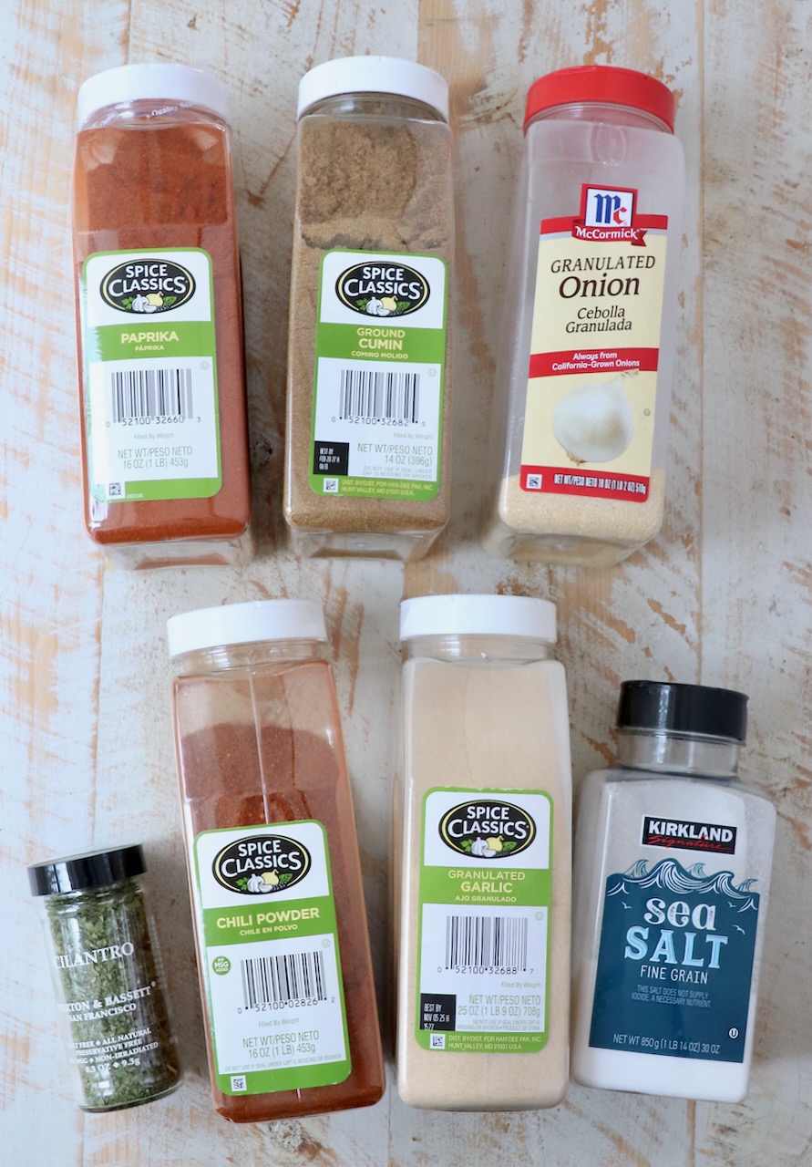 spices in plastic containers lined up on a white wood board