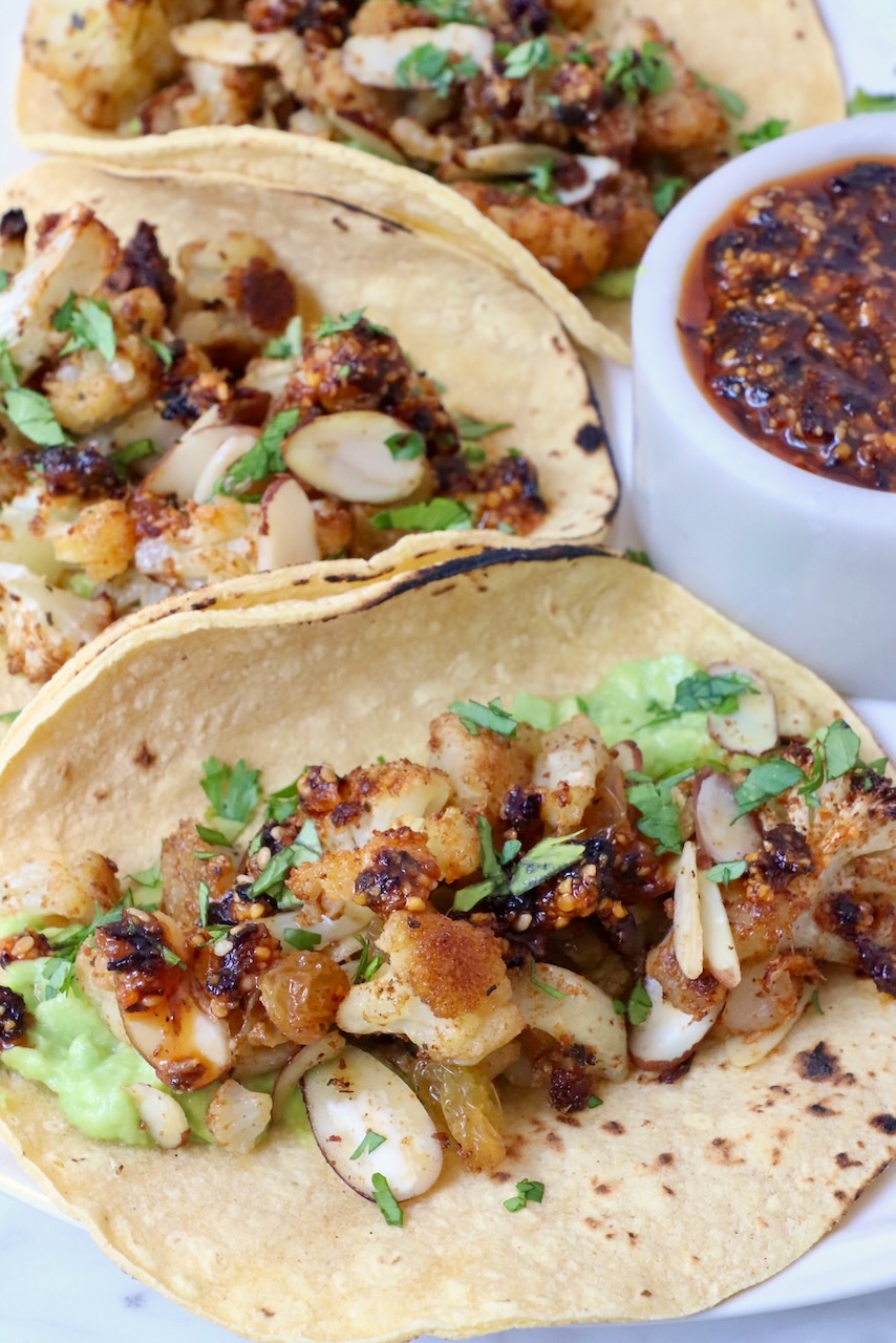 cauliflower tacos on a plate with a small bowl of salsa on the side