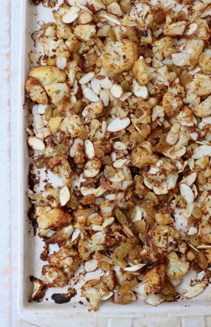 roasted seasoned cauliflower on baking sheet with almonds and raisins