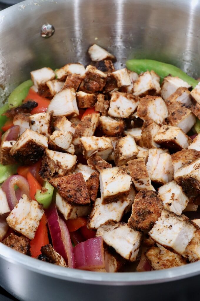 diced grilled chicken with sliced onions and bell peppers in a pot