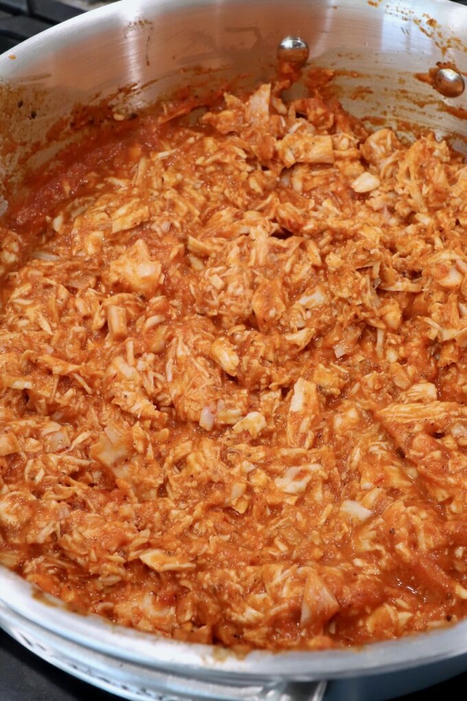 cooked, shredded chicken in tinga sauce in pan on the stove