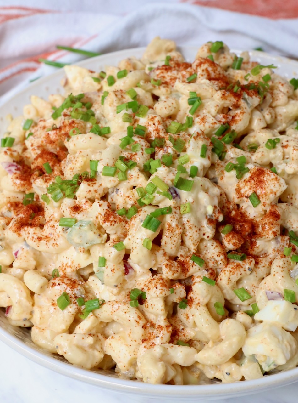 creamy pasta salad in bowl topped with paprika and diced chives