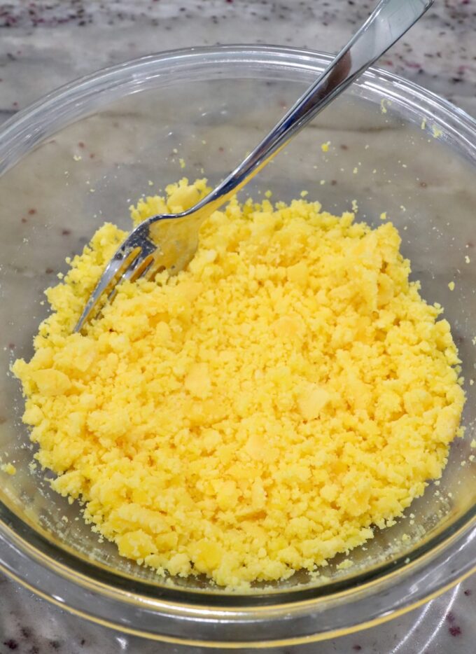 mashed egg yolks in a glass bowl with a fork