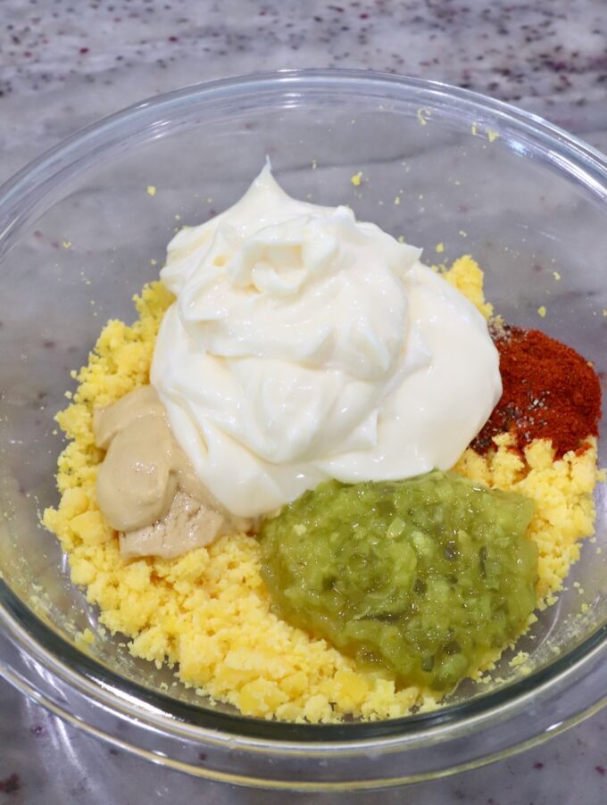 mashed egg yolks in a glass bowl with mayonnaise, relish, dijon mustard and spices