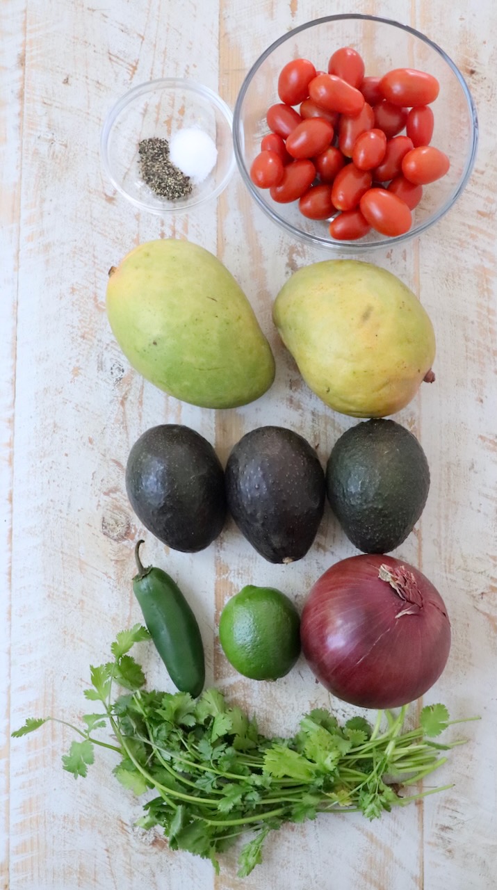ingredients for mango avocado salsa on white wood board
