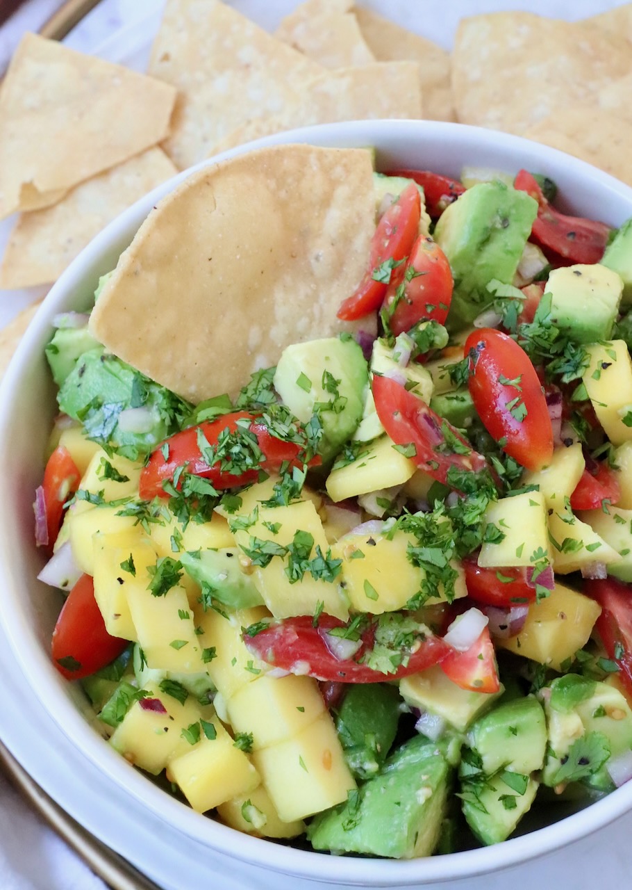 diced mango and avocado in bowl with tortilla chip