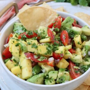 diced mango, avocado and tomatoes in bowl with tortilla chip