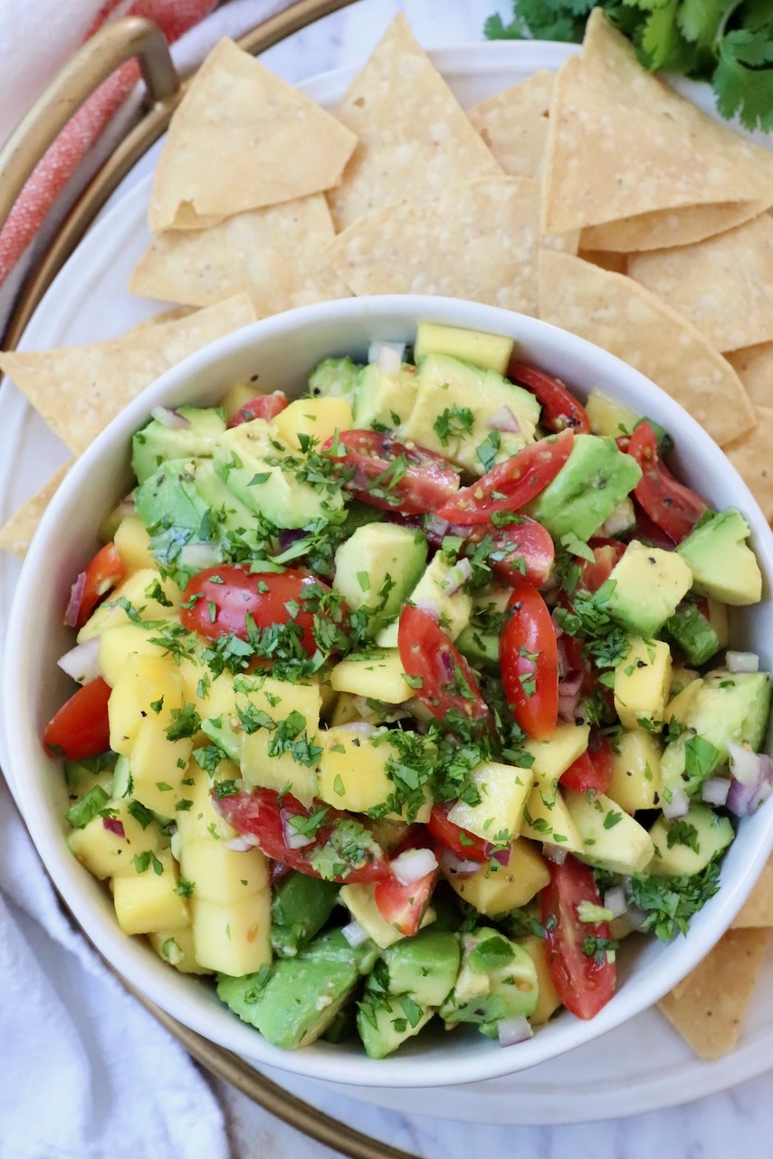 mango avocado salsa in bowl with tortilla chips around the bowl