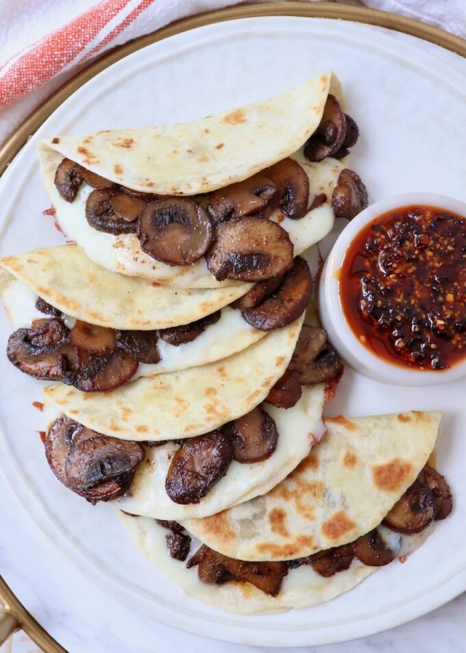 mushroom and cheese tacos on a plate with a small bowl of salsa macha on the side