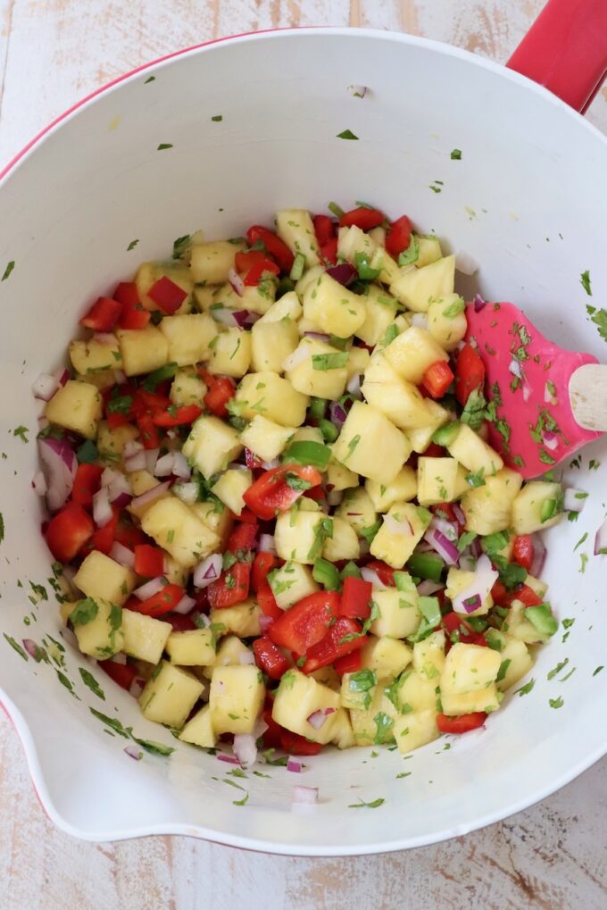 pineapple salsa in a large mixing bowl with a spatula