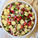 pineapple salsa in bowl surrounded by tortilla chips on a plate