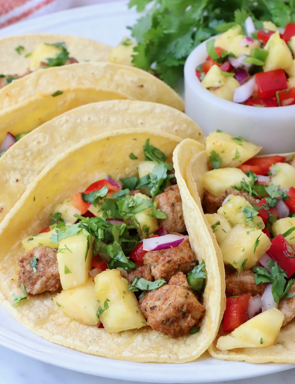 pork tacos topped with pineapple salsa on a plate