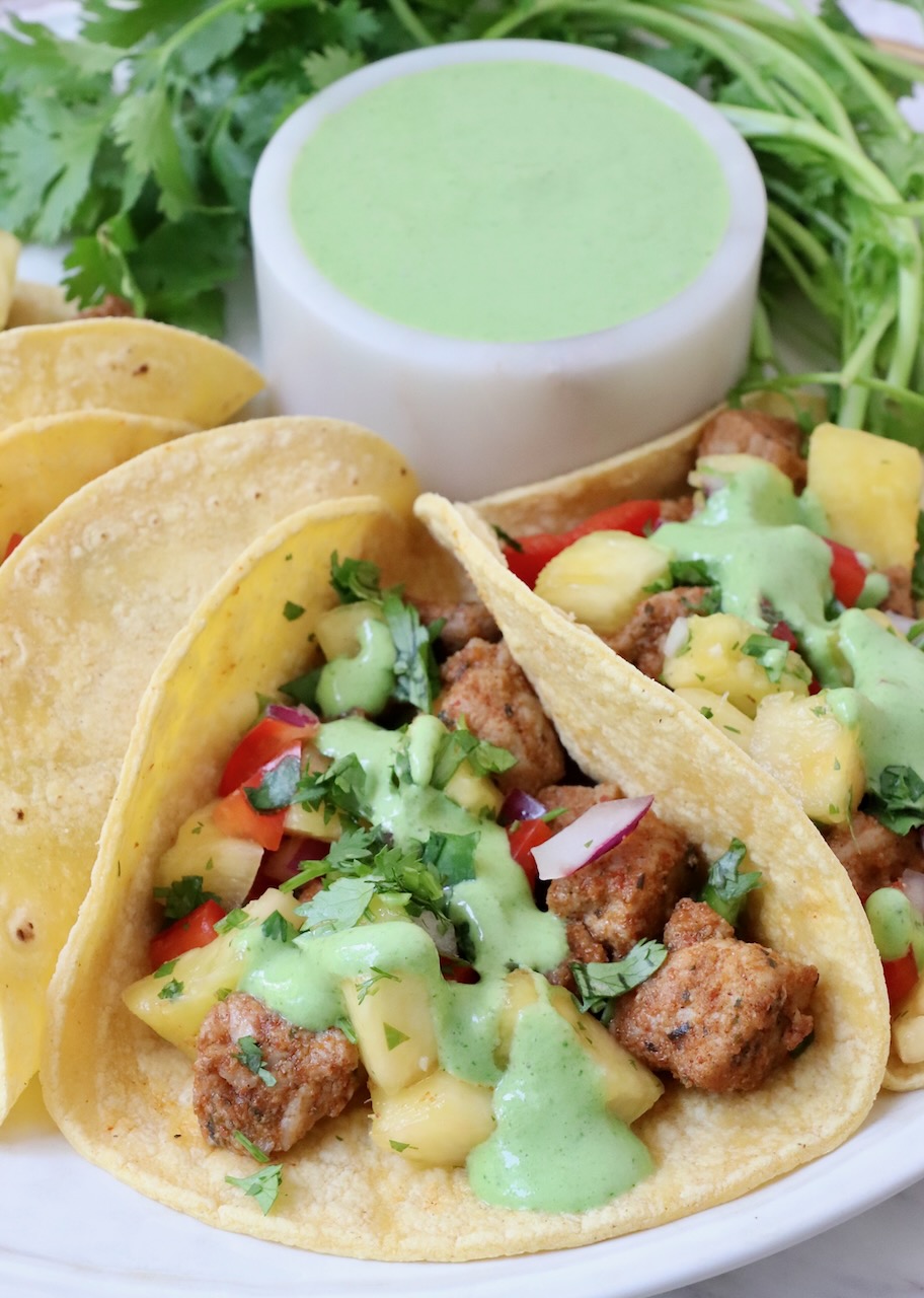 pork tacos topped with cilantro sauce on a plate