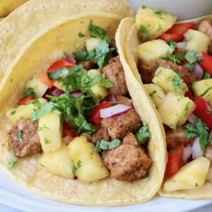pork tacos topped with pineapple salsa on a plate