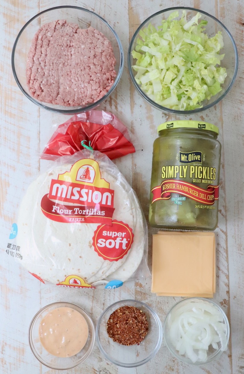 ingredients for smash burger tacos on a white wood board