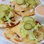 smash burger tacos on a plate with a small bowl of burger sauce on the side